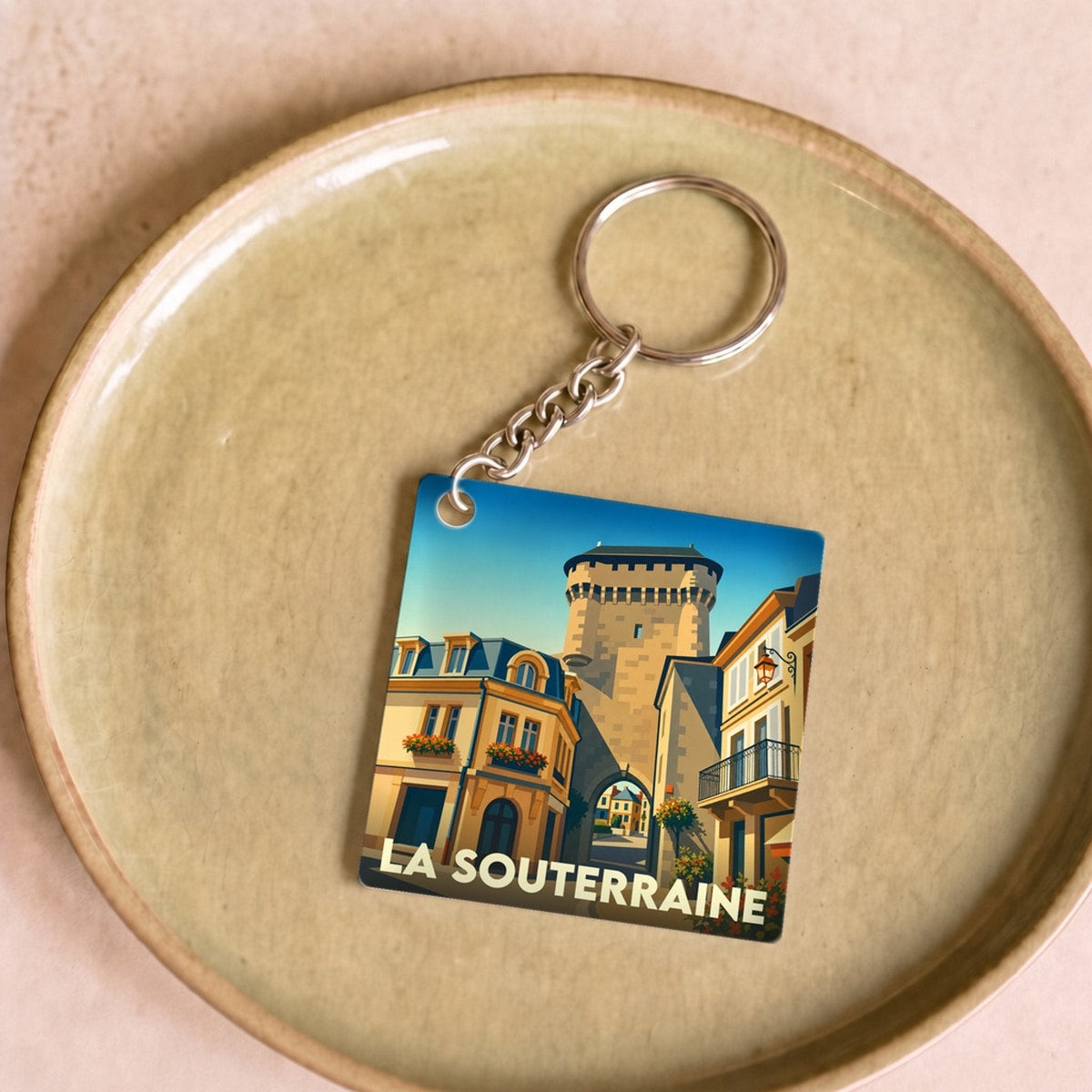 Porte-clés souvenir de la ville de La Souterraine avec une illustration stylisée de sa porte médiévale.