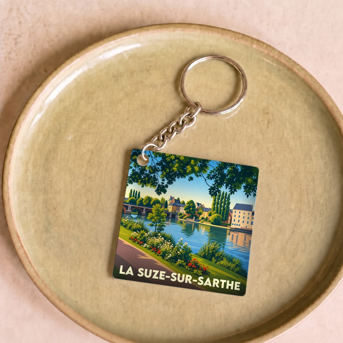 Porte-clés souvenir de la ville de La Suze-sur-Sarthe avec une illustration stylisée des bords de la Sarthe.