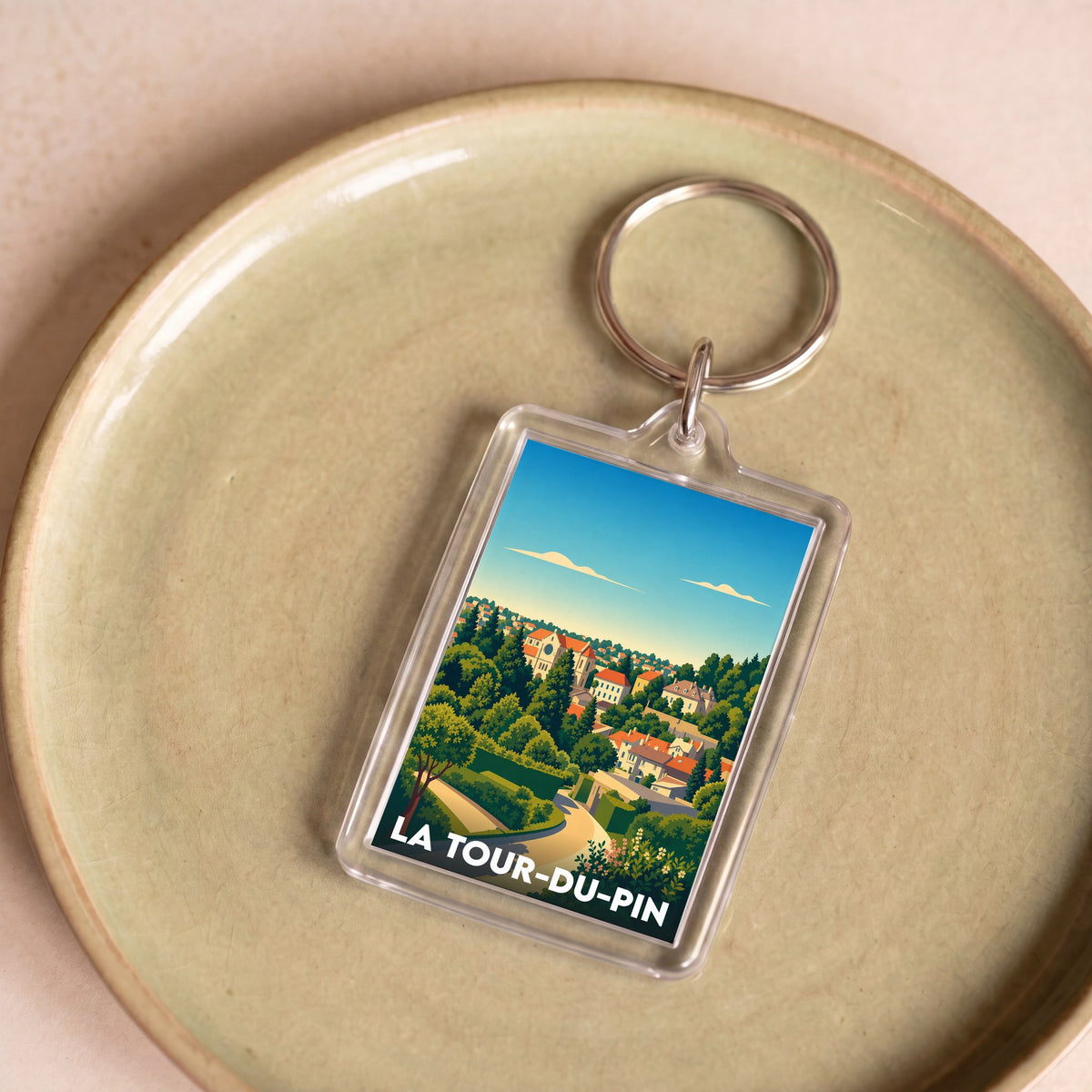 Porte-clés souvenir de la ville de La Tour-du-Pin avec une illustration stylisée de ses paysages.