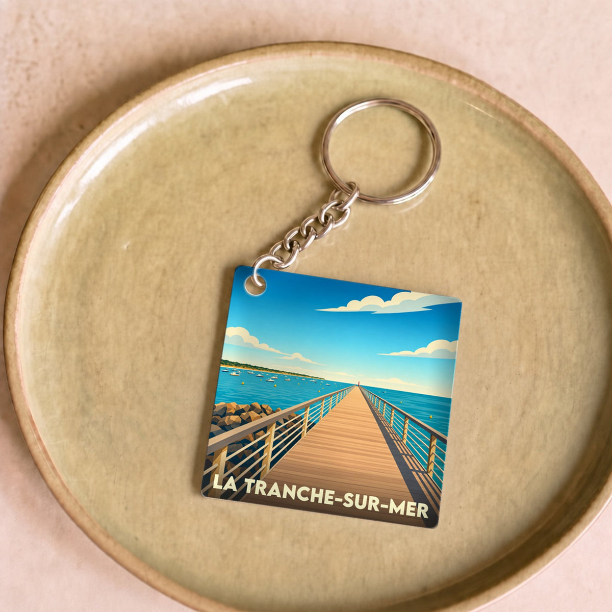 Porte-clés souvenir de la ville de La Tranche-sur-Mer avec une illustration stylisée d'une estacade en bord de mer.