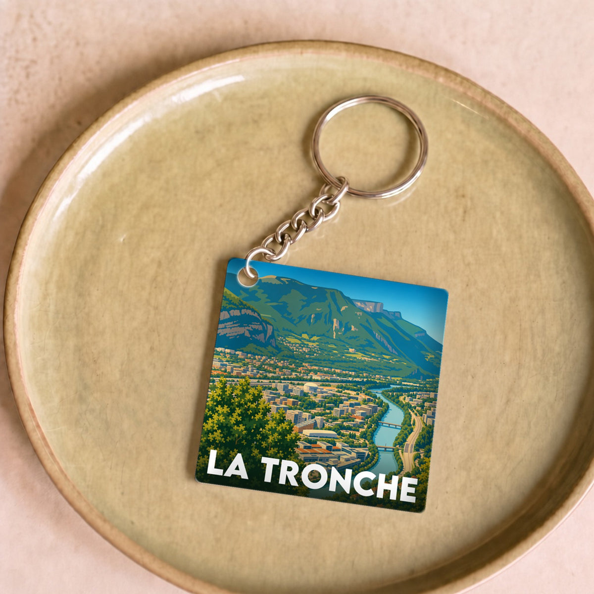 Porte-clés souvenir de la ville de La Tronche avec une illustration stylisée d'un paysage montagneux.