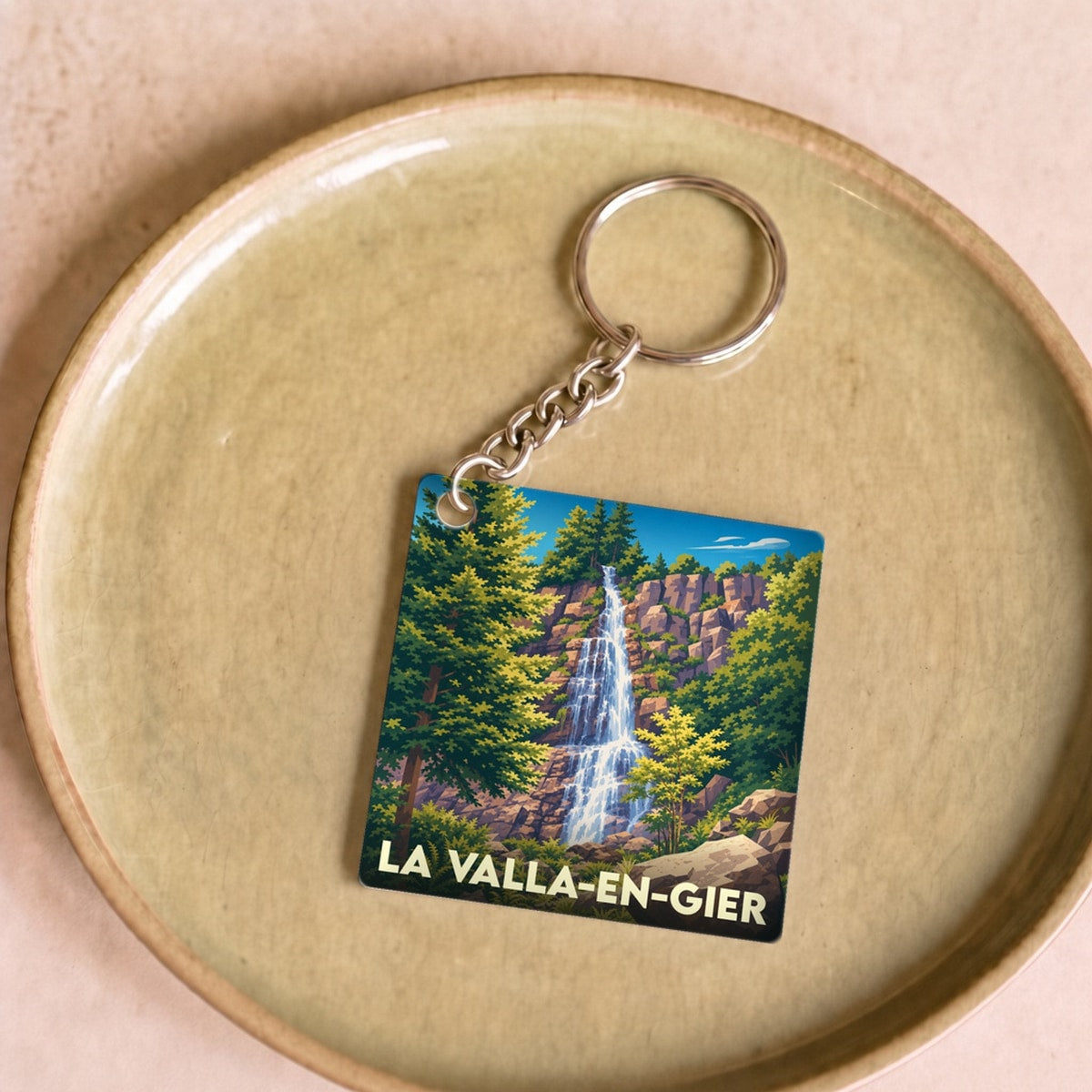 Porte-clés souvenir de la ville de La Valla-en-Gier avec une illustration stylisée d'une cascade.