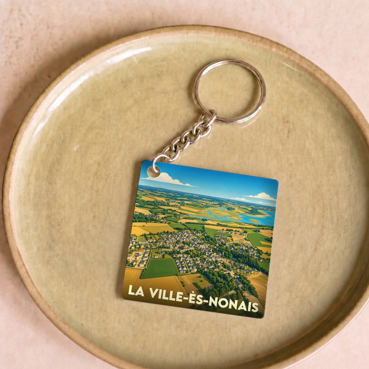 Porte-clés souvenir de La Ville-ès-Nonais avec une vue aérienne illustrée de la commune.
