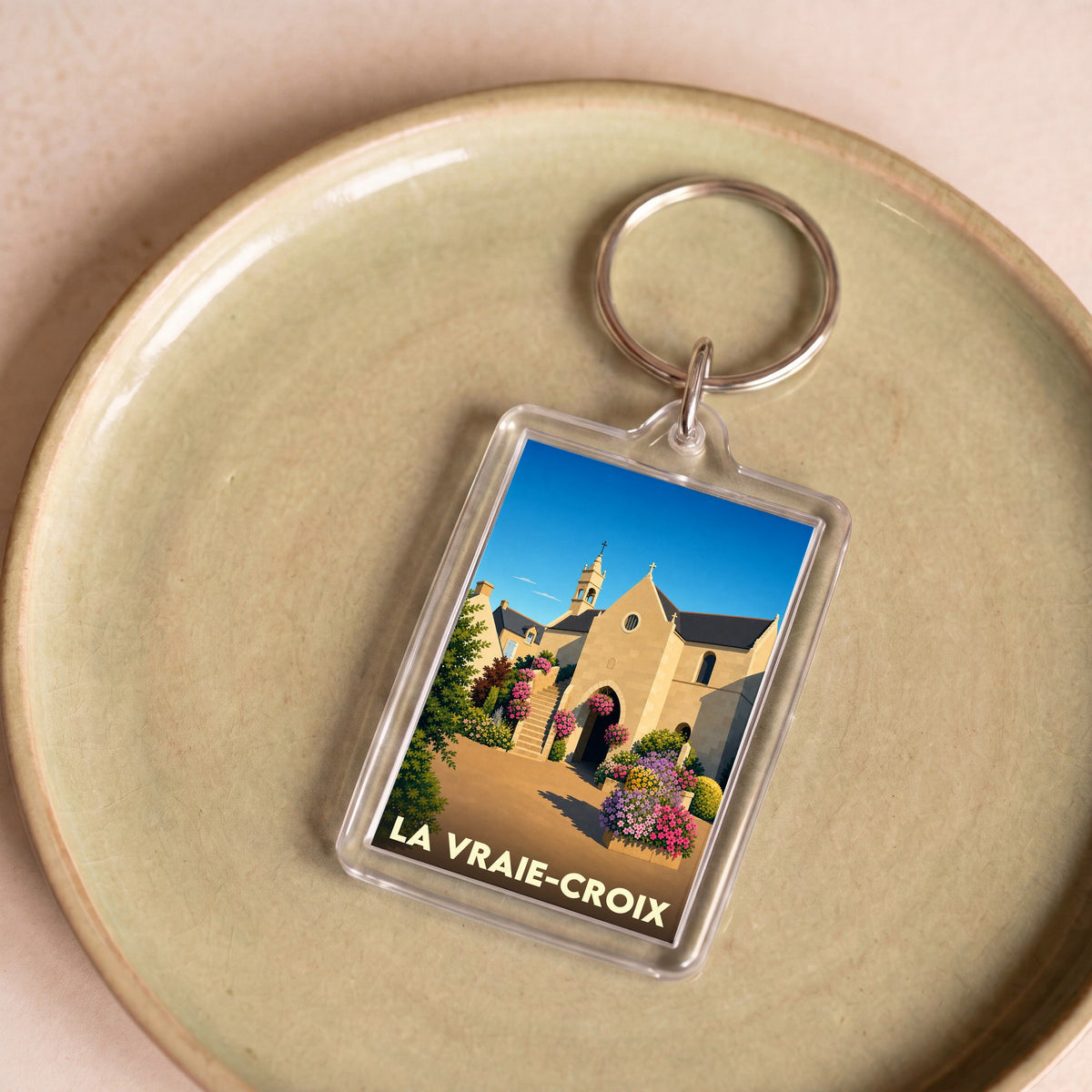 Porte-clés souvenir de la commune de La Vraie-Croix avec une illustration stylisée de sa chapelle fleurie.