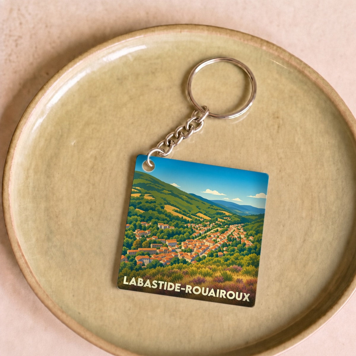 Porte-clés souvenir de la ville de Labastide-Rouairoux avec une illustration paysagère stylisée.