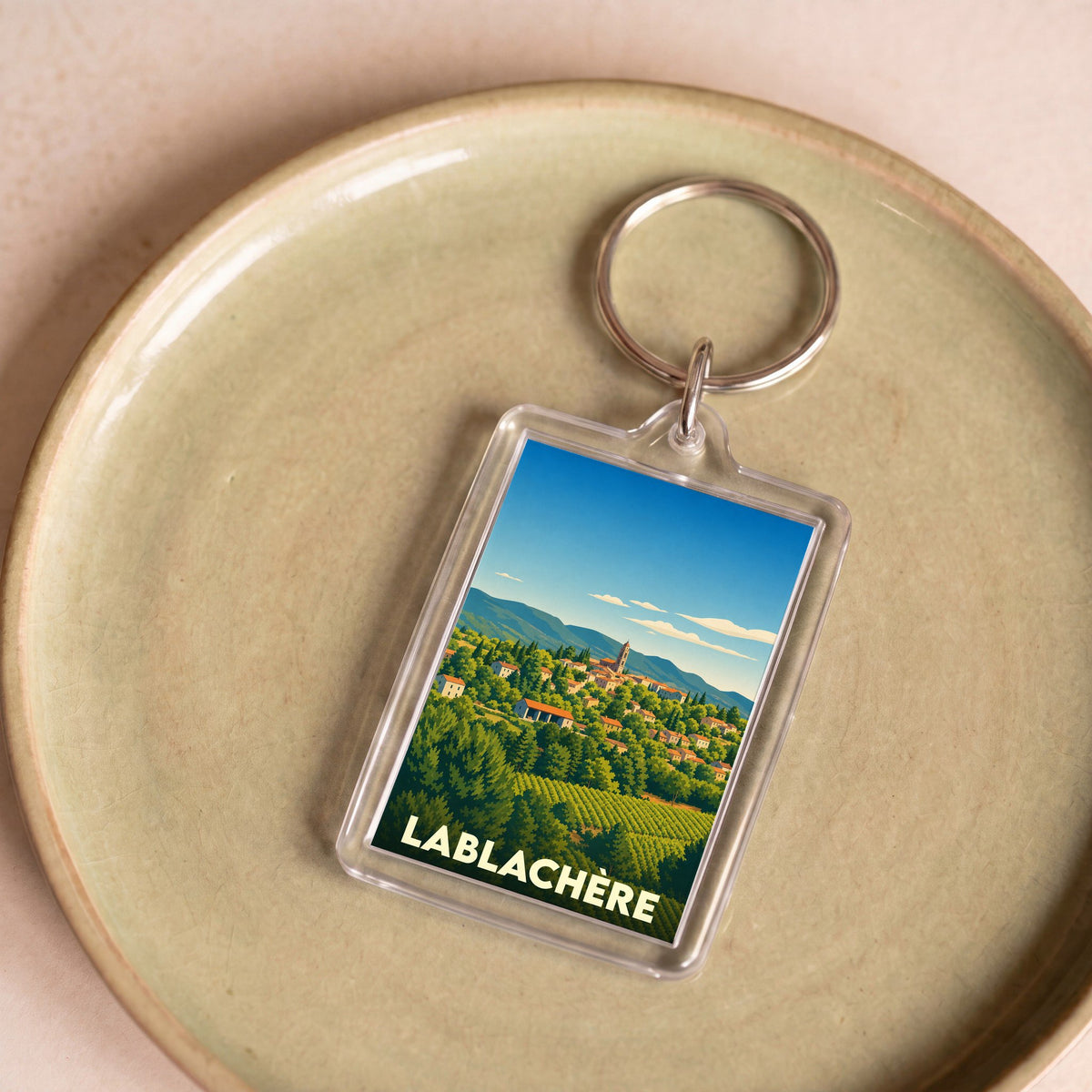 Porte-clés souvenir de la ville de Lablachère avec une illustration stylisée de son paysage vallonné.