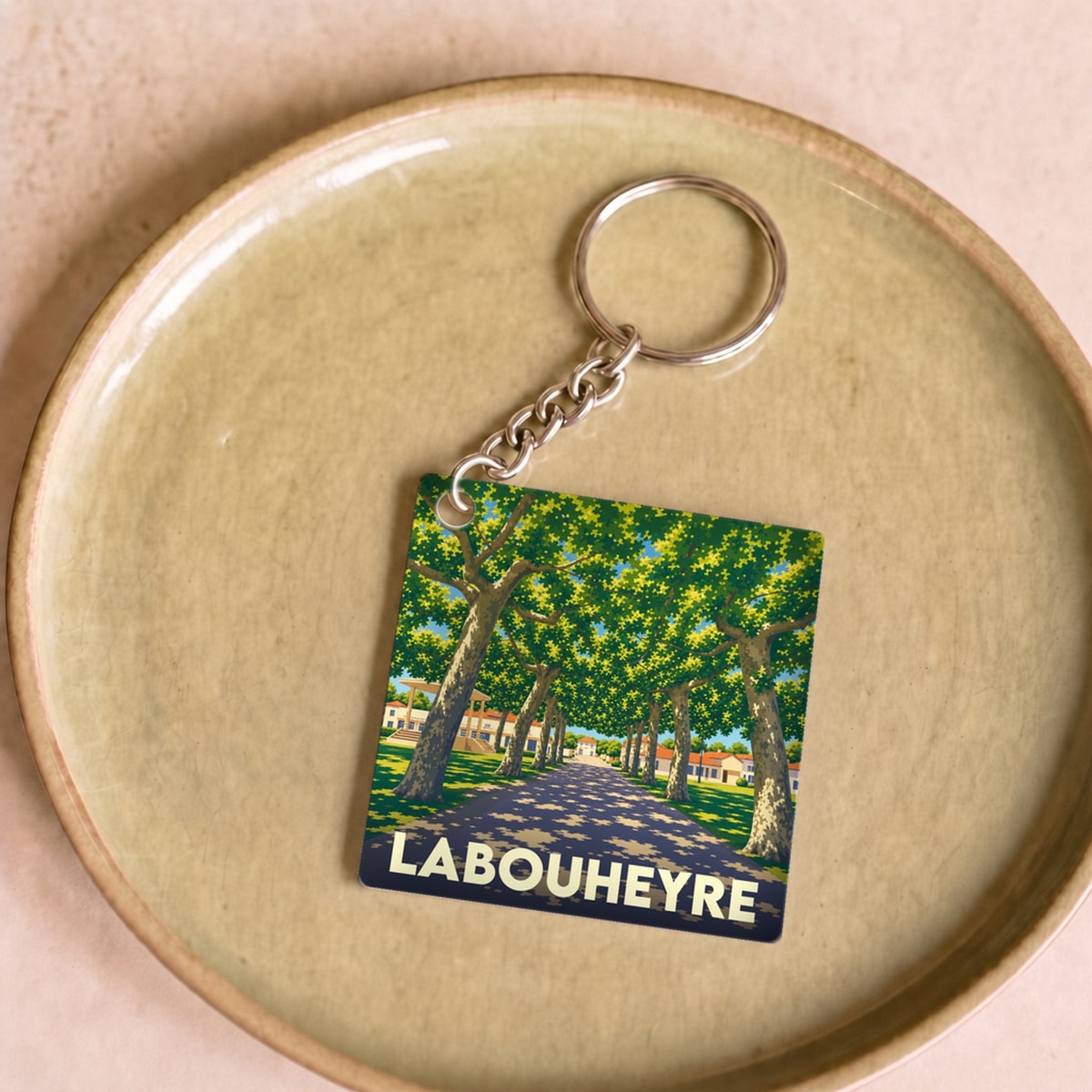 Porte-clés souvenir de la ville de Labouheyre avec une illustration stylisée d'une allée d'arbres.
