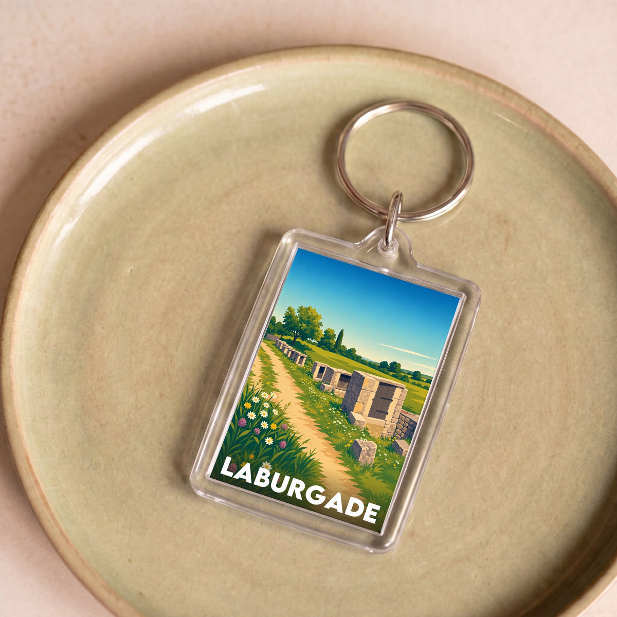 Porte-clés souvenir de la ville de Laburgade avec une illustration stylisée d'un paysage.
