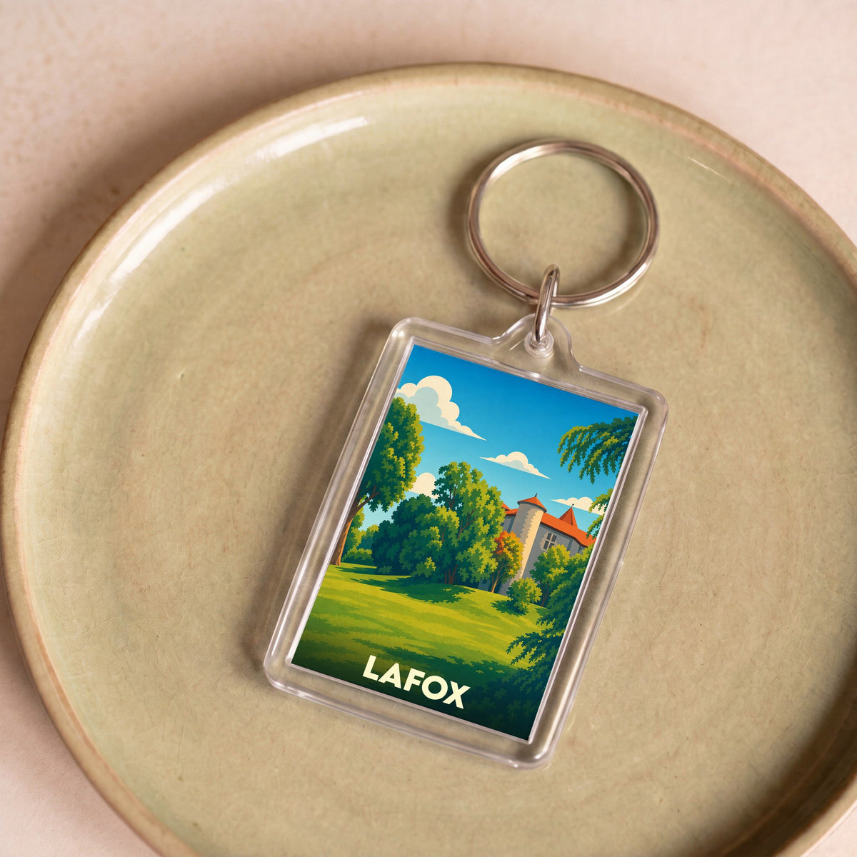 Porte-clés souvenir de la ville de Lafox avec une illustration stylisée d'un château dans un parc arboré.