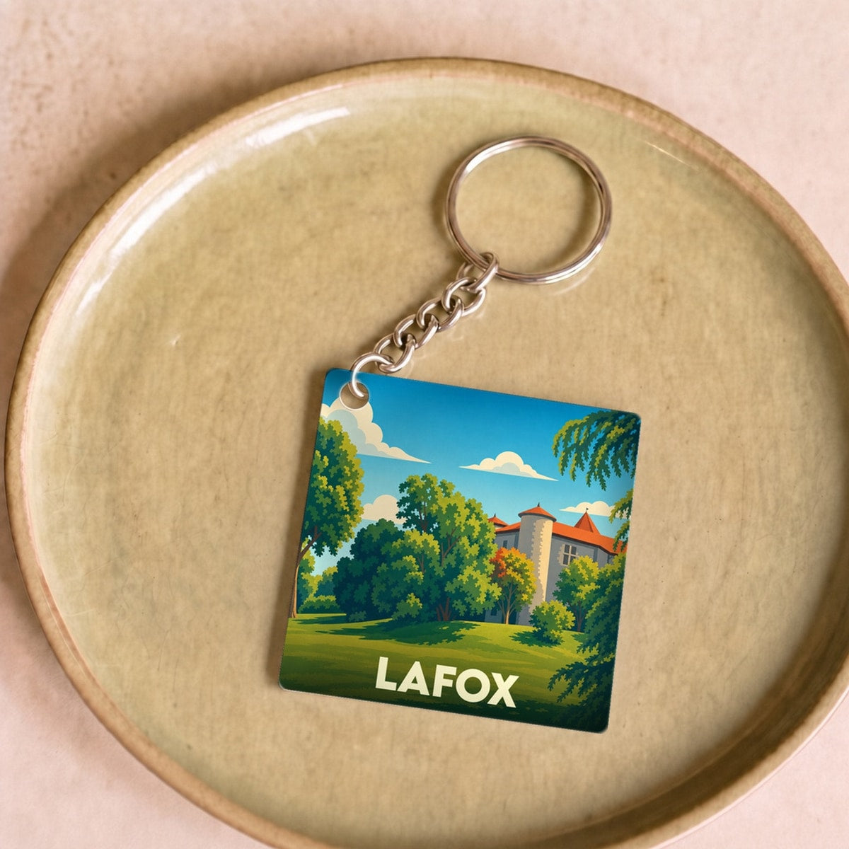 Porte-clés souvenir de la ville de Lafox avec une illustration stylisée d'un château dans un parc arboré.