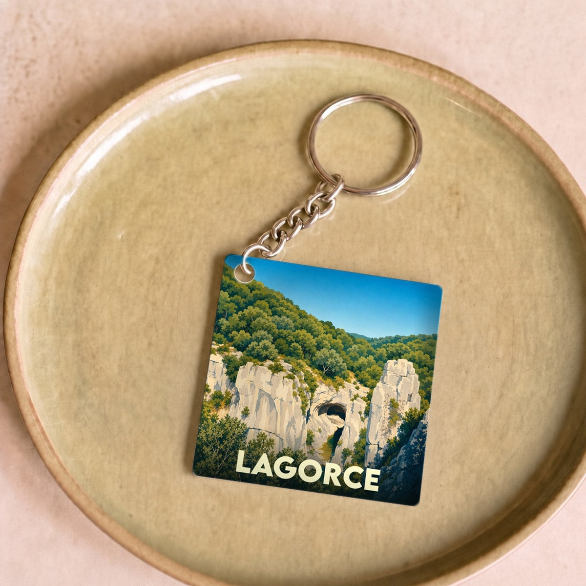 Porte-clés souvenir de la ville de Lagorce avec une illustration stylisée d'un paysage rocheux.