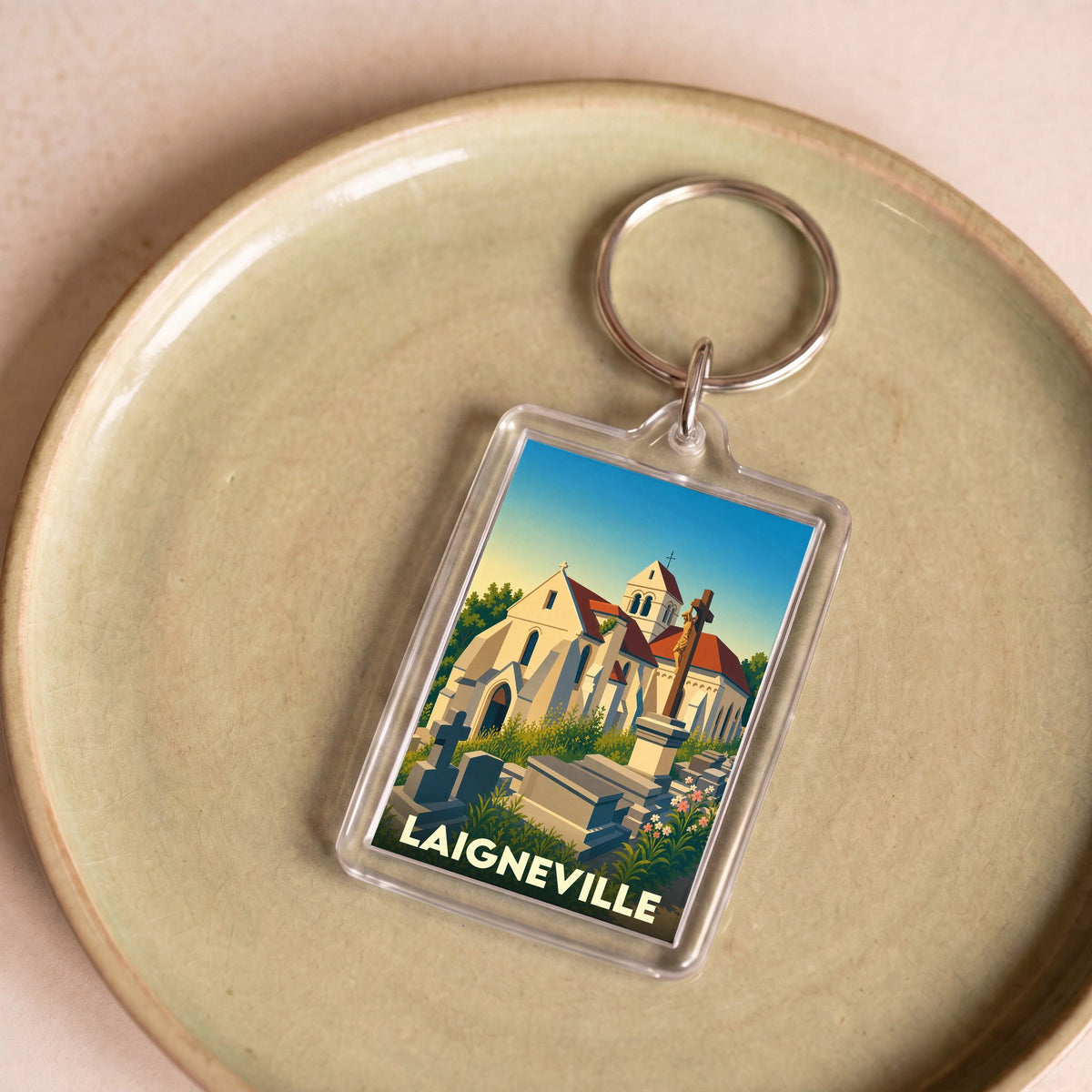 Porte-clés souvenir de la ville de Laigneville avec une illustration stylisée de son église et de son cimetière.