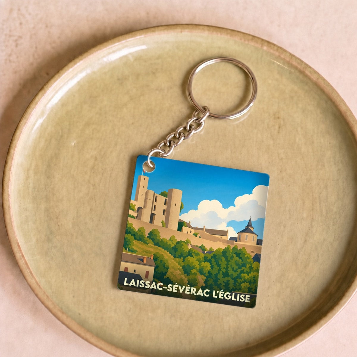 Porte-clés souvenir de la commune de Laissac-Sévérac l'Église avec une illustration stylisée de son château.