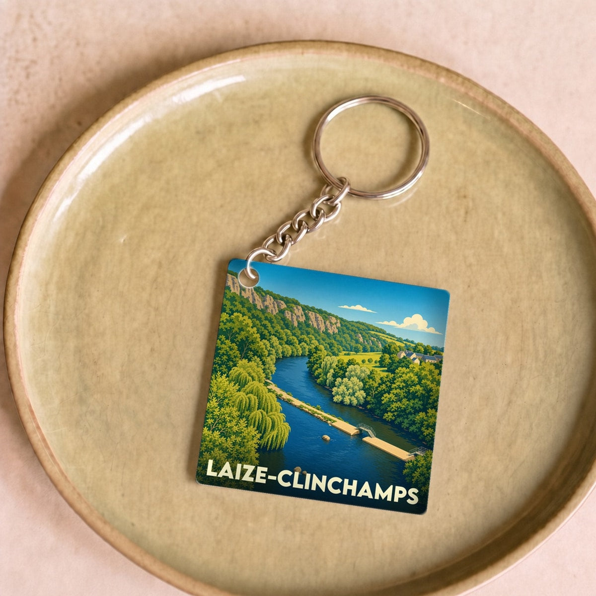 Porte-clés souvenir de la ville de Laize-Clinchamps avec une illustration stylisée d'un paysage de rivière.