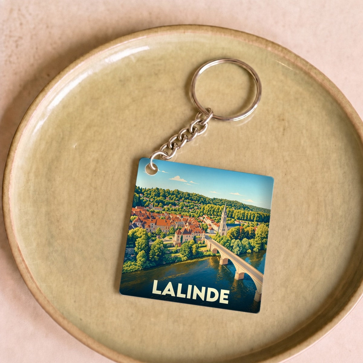 Porte-clés souvenir de la ville de Lalinde avec une illustration stylisée de son pont et de ses toits.