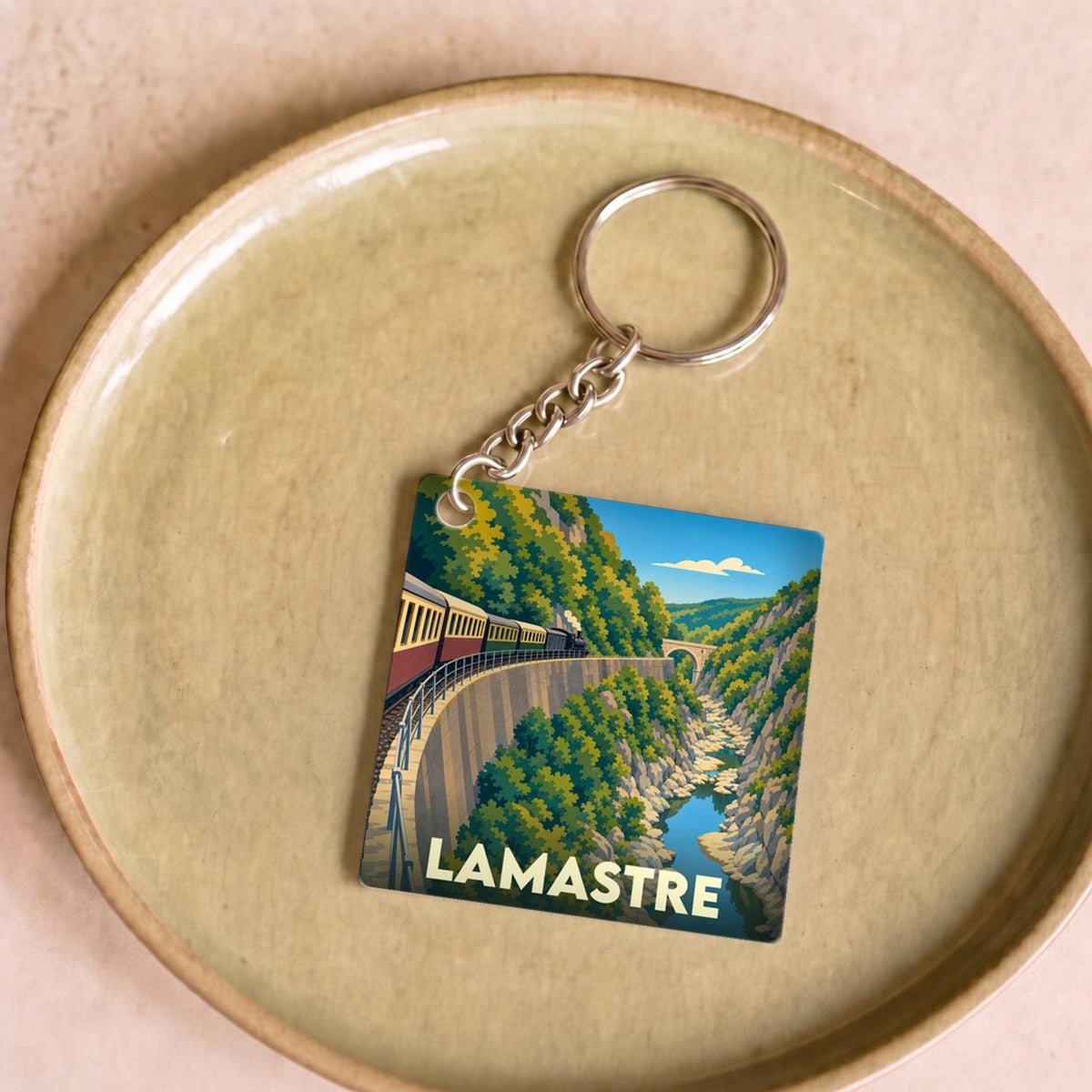 Porte-clés souvenir de la ville de Lamastre avec une illustration stylisée d'un train serpentant dans les gorges.