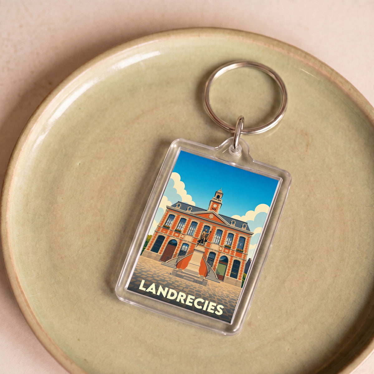 Porte-clés souvenir de la ville de Landrecies avec une illustration stylisée de son hôtel de ville.