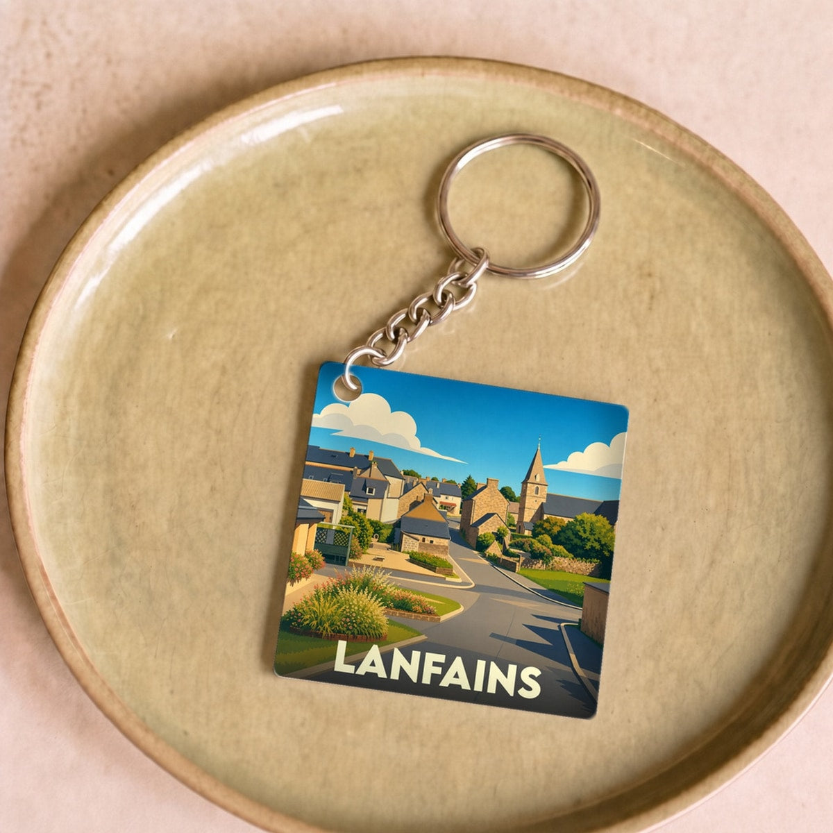 Porte-clés souvenir de la ville de Lanfains avec une illustration stylisée.