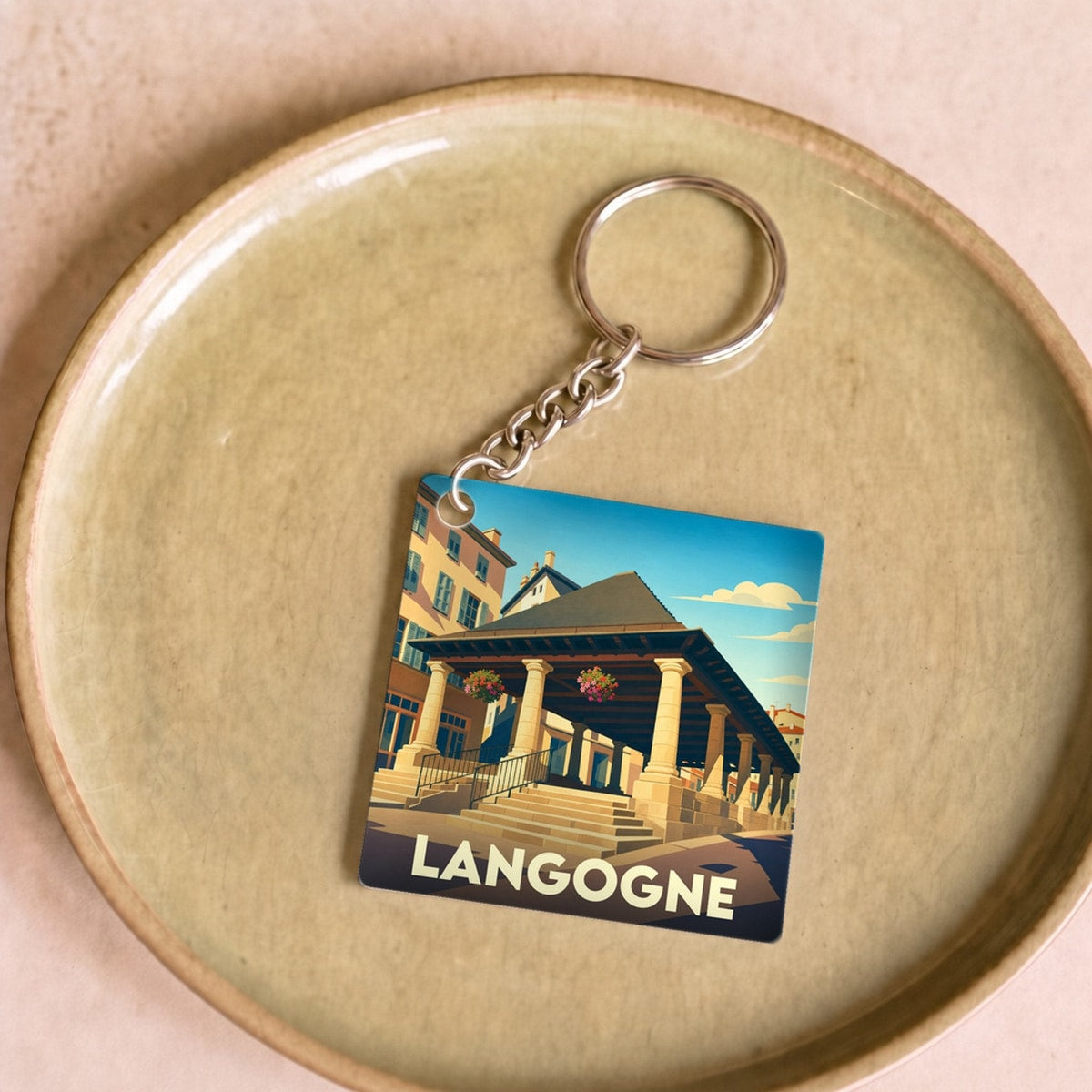 Porte-clés souvenir de la ville de Langogne avec une illustration stylisée de ses halles historiques.