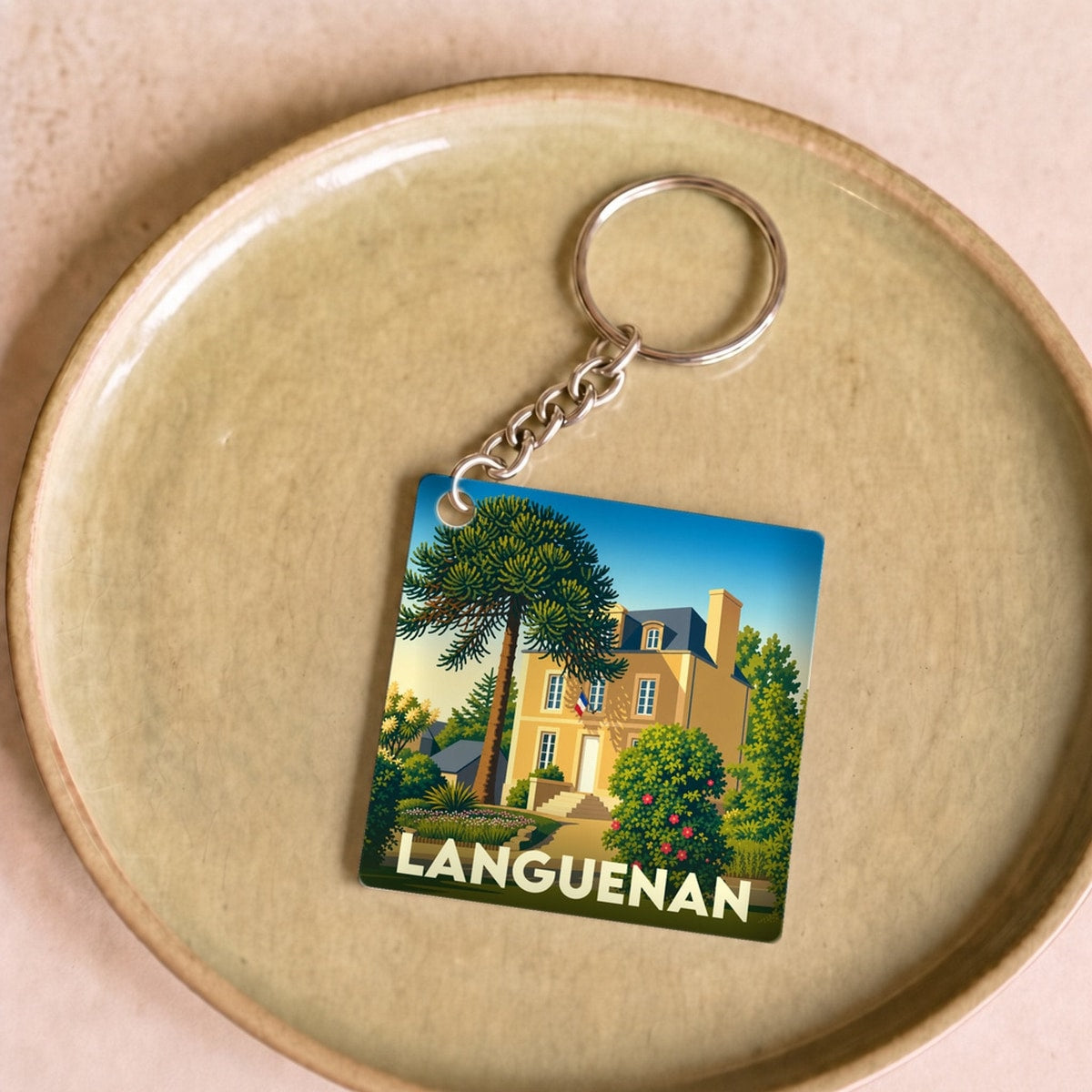 Porte-clés souvenir de la ville de Languenan avec une illustration stylisée d'une maison et d'un araucaria.