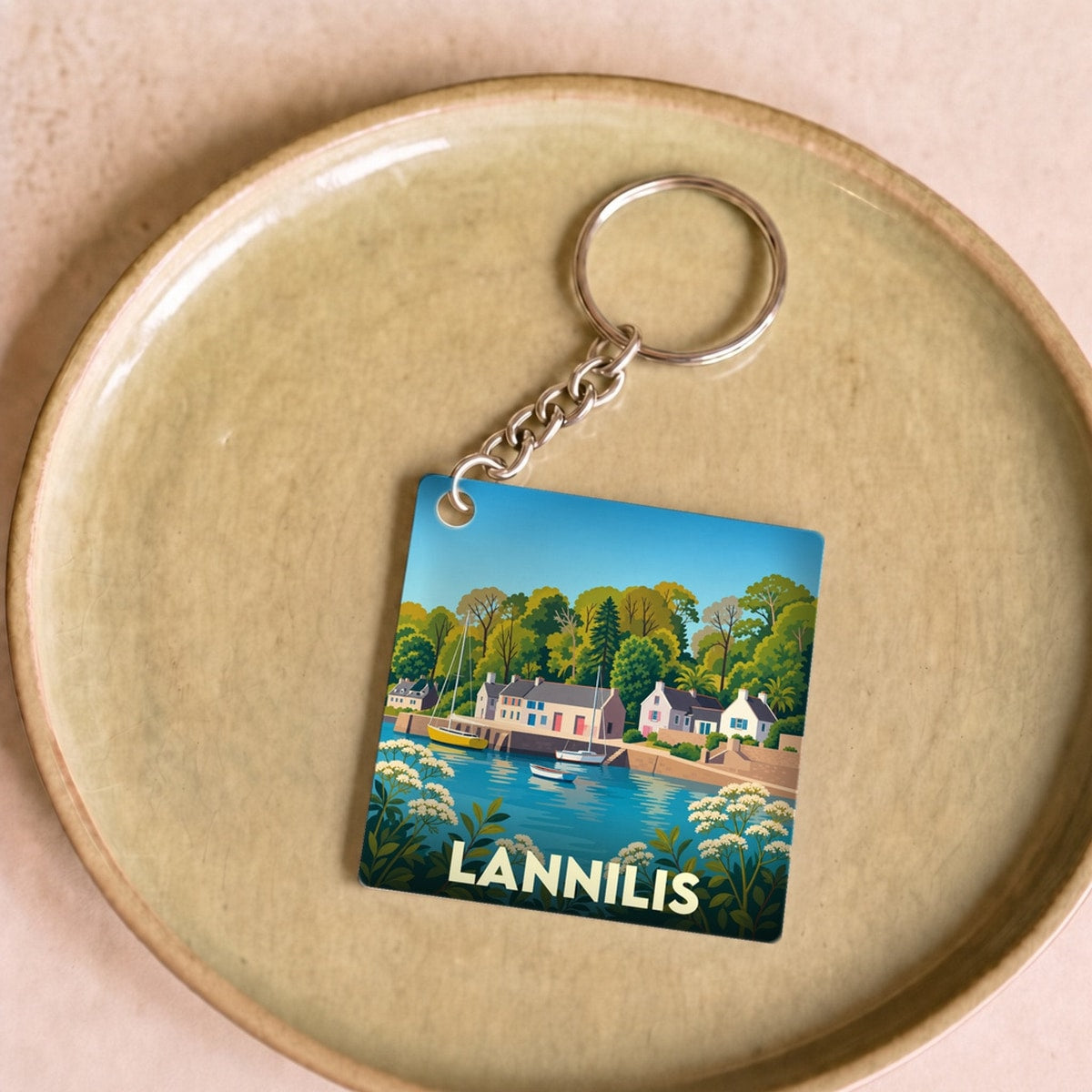 Porte-clés souvenir de la ville de Lannilis avec une illustration stylisée d'un bord de mer.