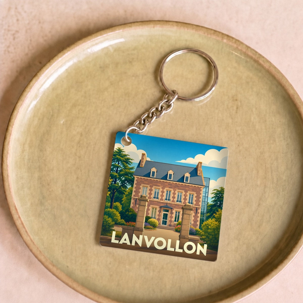 Porte-clés souvenir de la ville de Lanvollon avec une illustration stylisée d'un manoir breton.