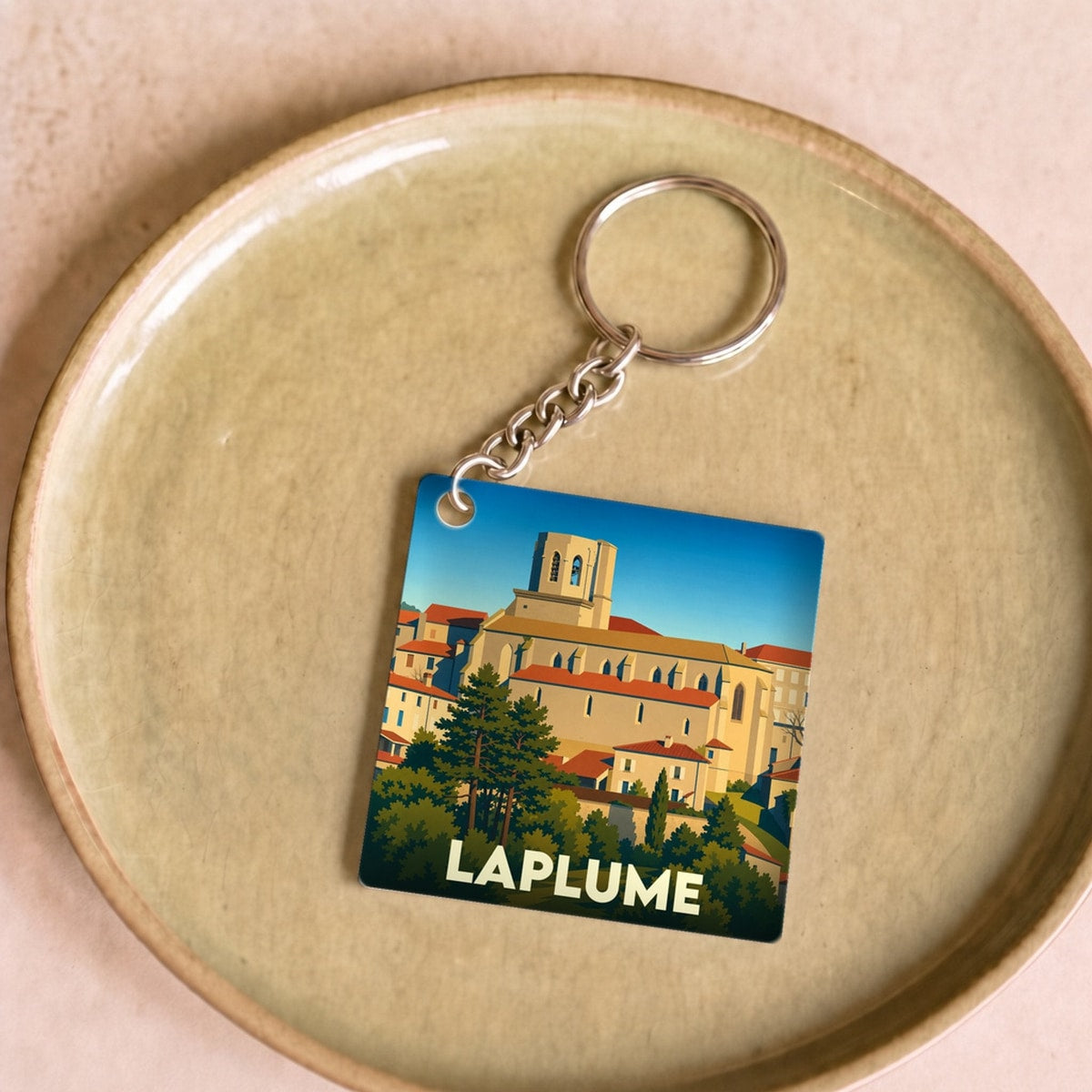 Porte-clés souvenir de la ville de Laplume avec une illustration stylisée.