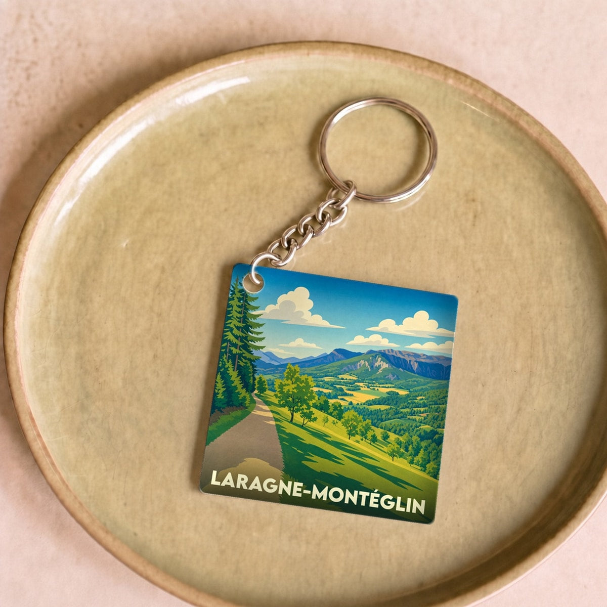 Porte-clés souvenir de la ville de Laragne-Montéglin avec une illustration de paysage montagneux stylisée.