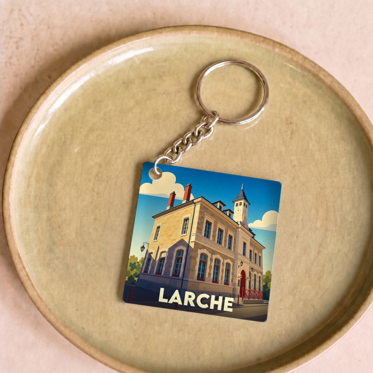 Porte-clés souvenir de la ville de Larche avec une illustration stylisée de son architecture.