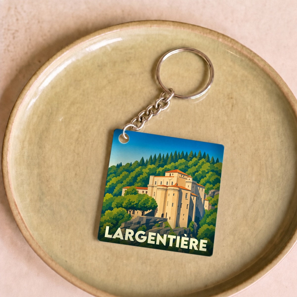 Porte-clés souvenir de la ville de Largentière avec une illustration stylisée de son château médiéval.