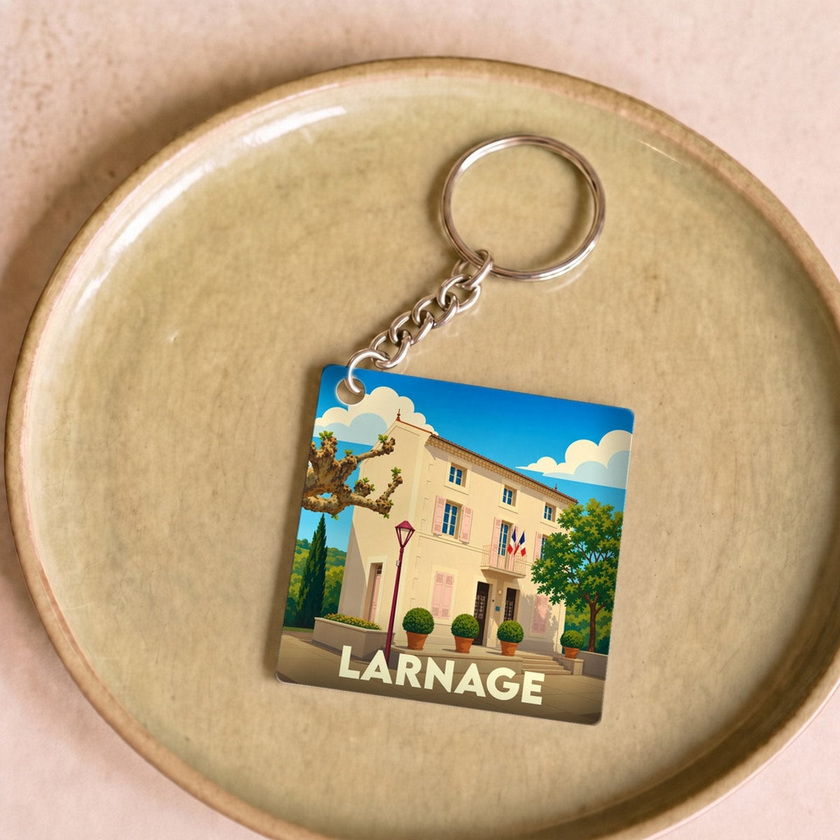 Porte-clés souvenir de la ville de Larnage avec une illustration stylisée d'un bâtiment provençal.