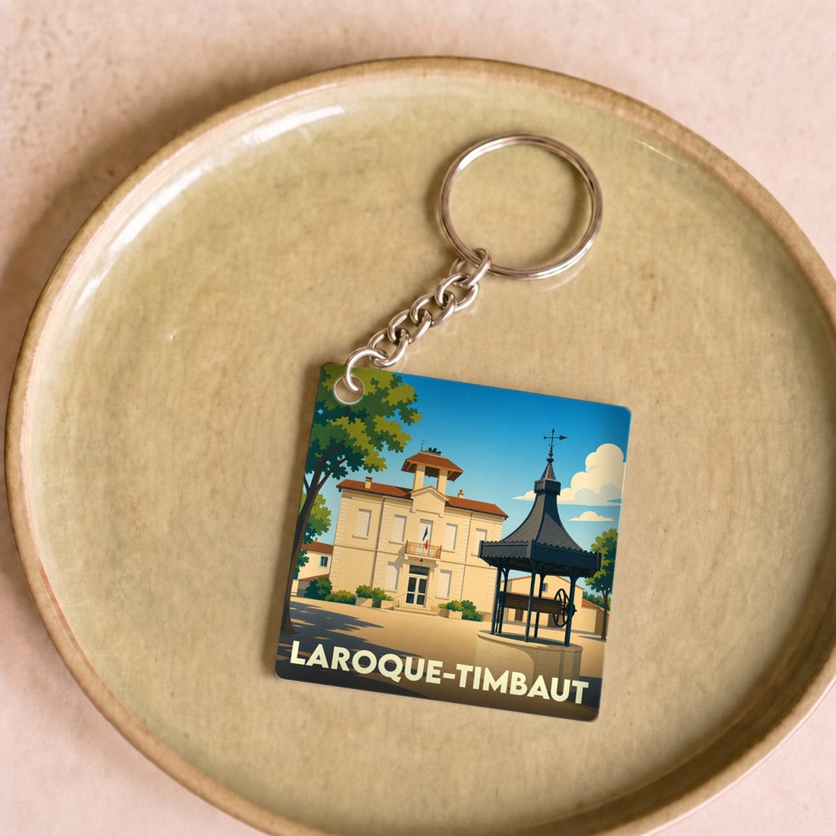 Porte-clés souvenir de la ville de Laroque-Timbaut avec une illustration stylisée.