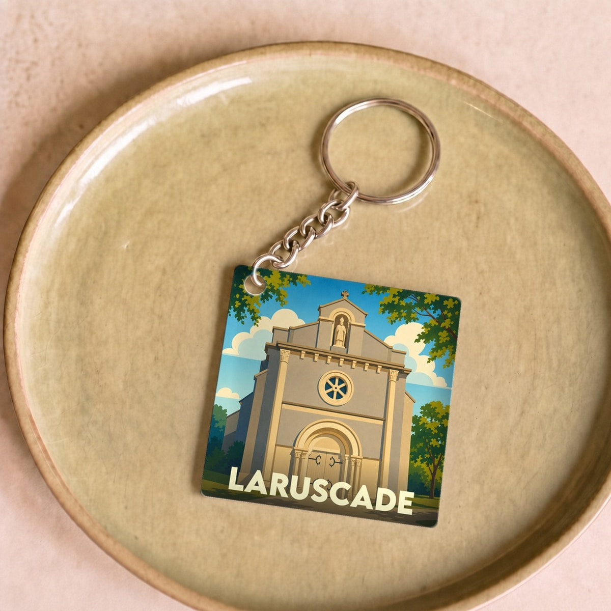Porte-clés souvenir de la ville de Laruscade avec une illustration stylisée de son église.