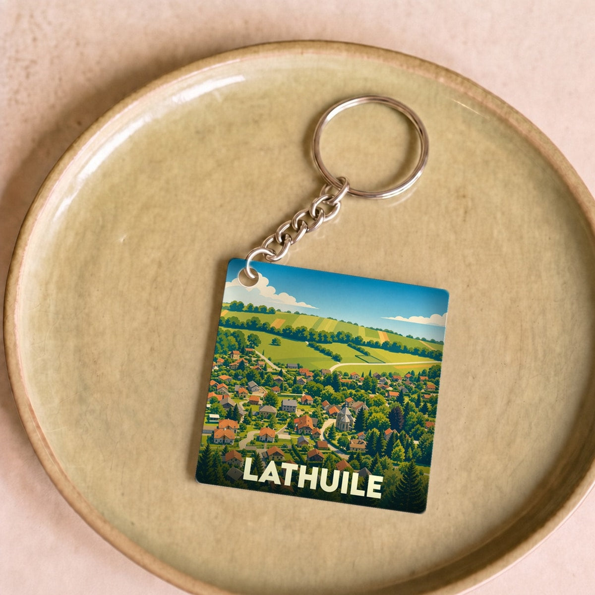 Porte-clés souvenir de la ville de Lathuile avec une illustration stylisée de son paysage urbain et verdoyant.
