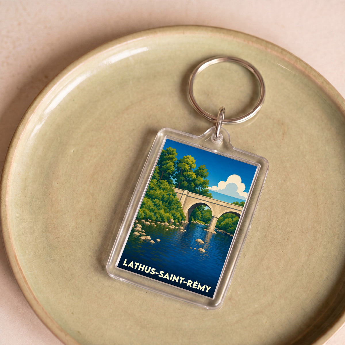 Porte-clés souvenir de la ville de Lathus-Saint-Rémy avec une illustration stylisée d'un pont en pierre au-dessus d'une rivière.