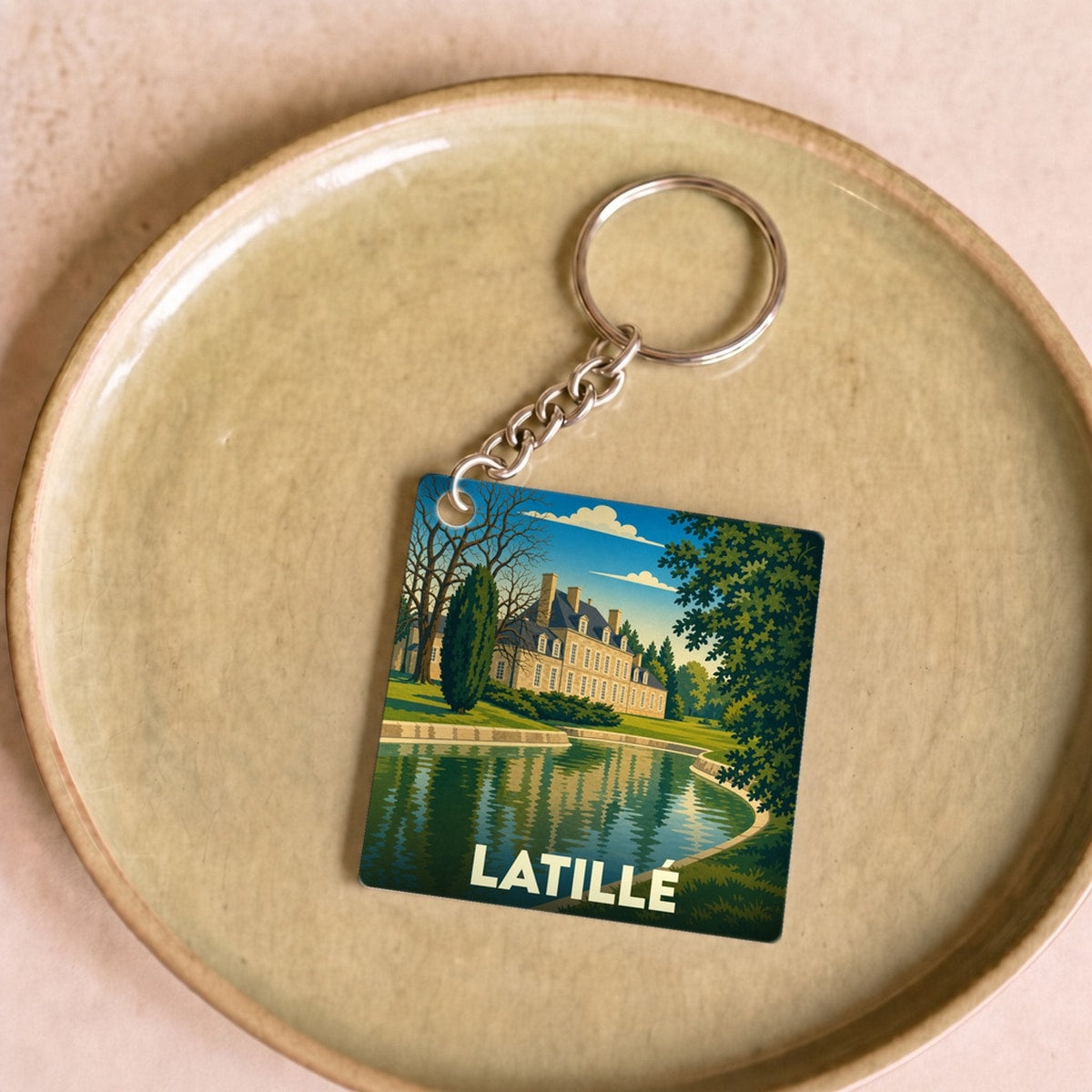 Porte-clés souvenir de la ville de Latillé avec une illustration stylisée de son château se reflétant dans l'eau.