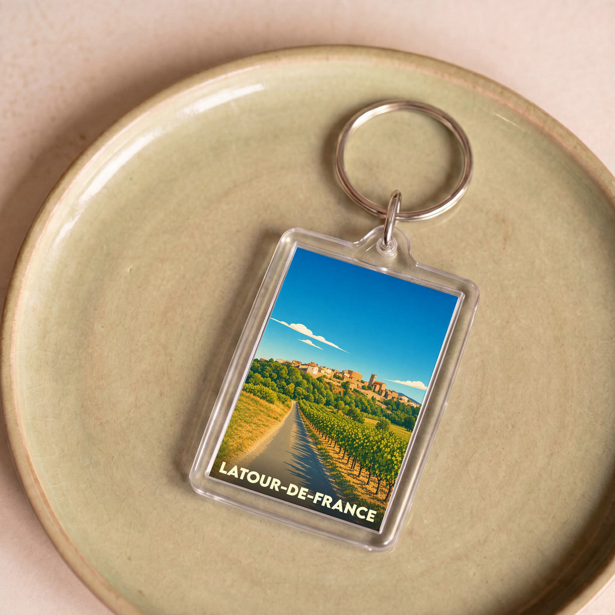 Porte-clés souvenir de la ville de Latour-de-France avec une illustration stylisée de ses paysages de vignobles.