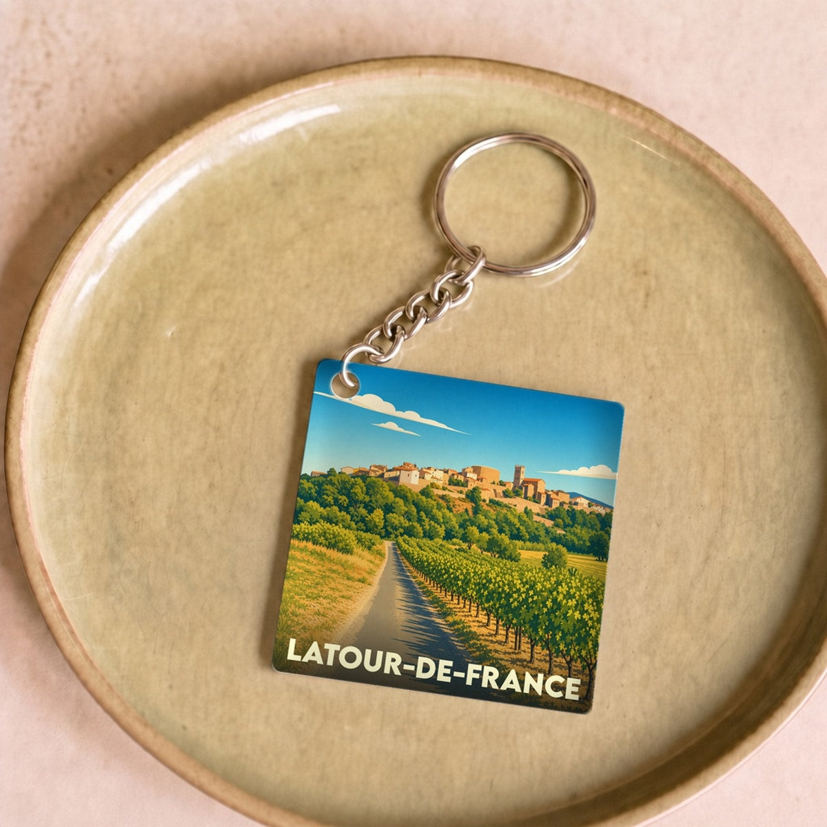 Porte-clés souvenir de la ville de Latour-de-France avec une illustration stylisée de ses paysages de vignobles.