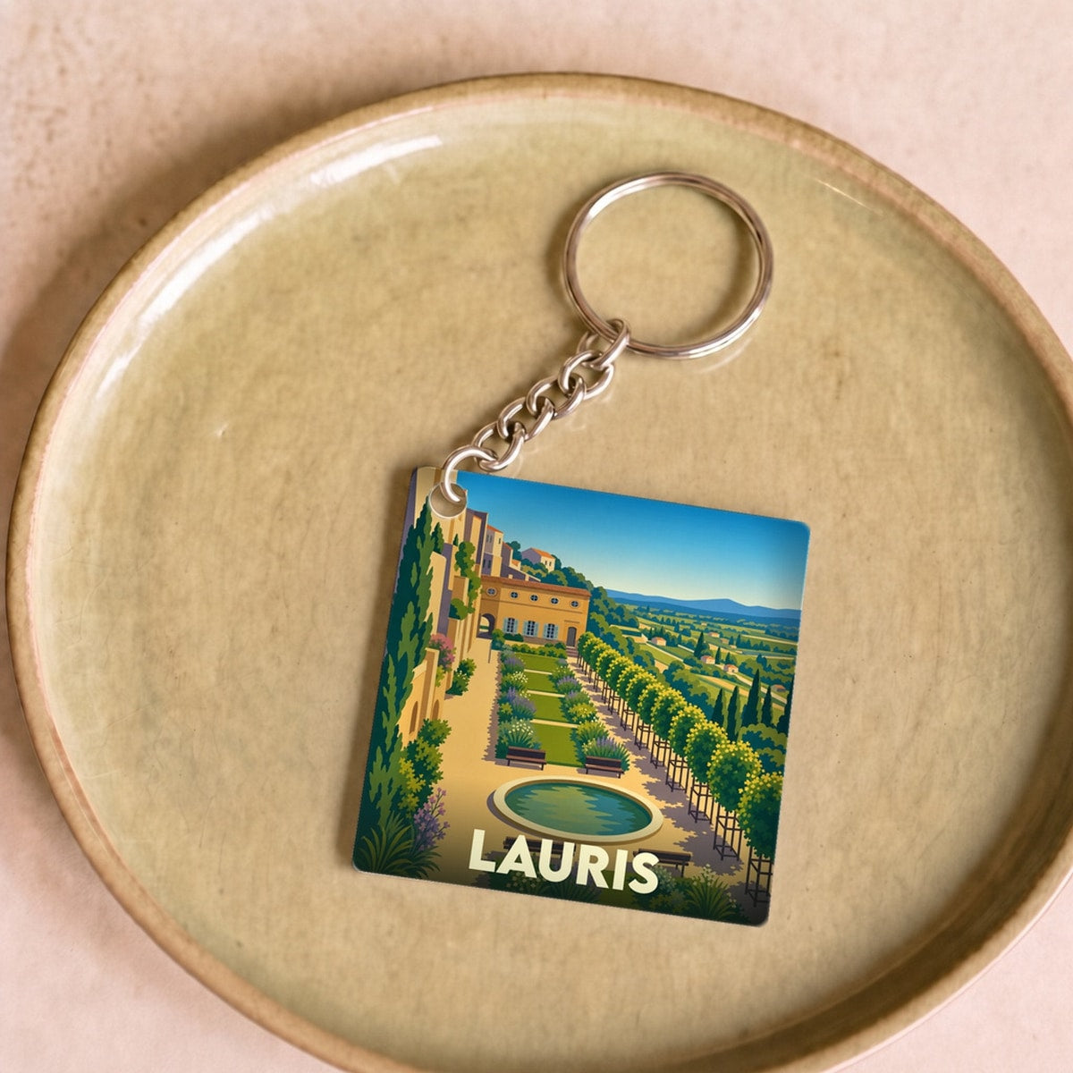 Porte-clés souvenir de la ville de Lauris avec une illustration stylisée d'un jardin en terrasses.