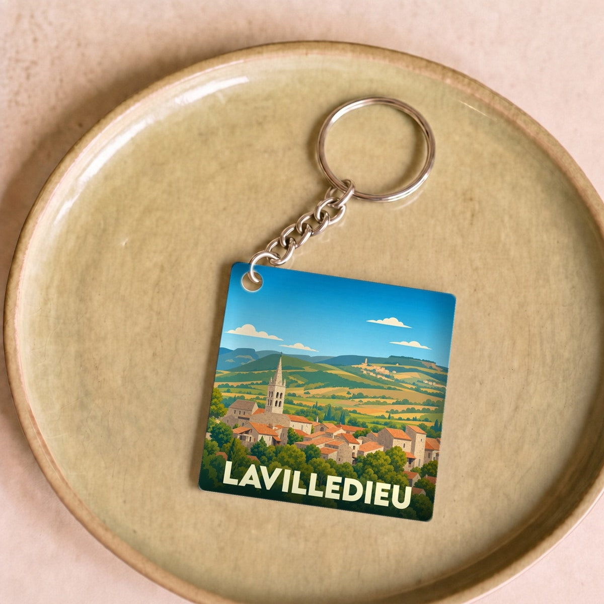 Porte-clés souvenir de la ville de Lavilledieu avec une illustration stylisée de son paysage urbain et vallonné.