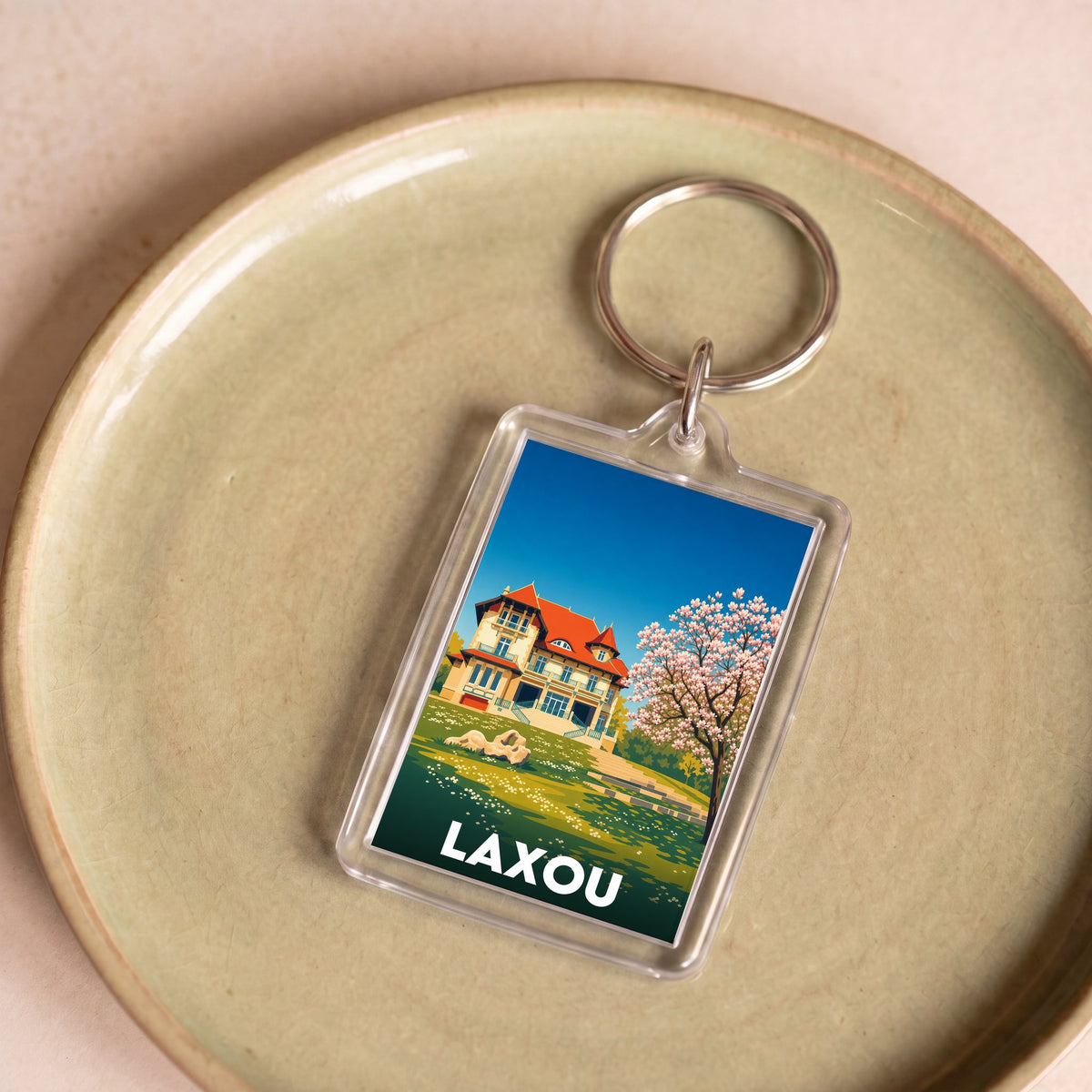 Porte-clés souvenir de la ville de Laxou avec une illustration stylisée.