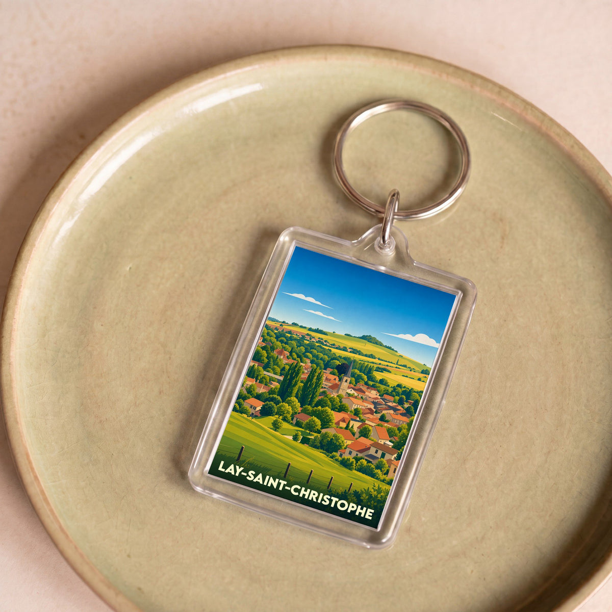 Porte-clés souvenir de la ville de Lay-Saint-Christophe avec une illustration stylisée de son paysage champêtre.