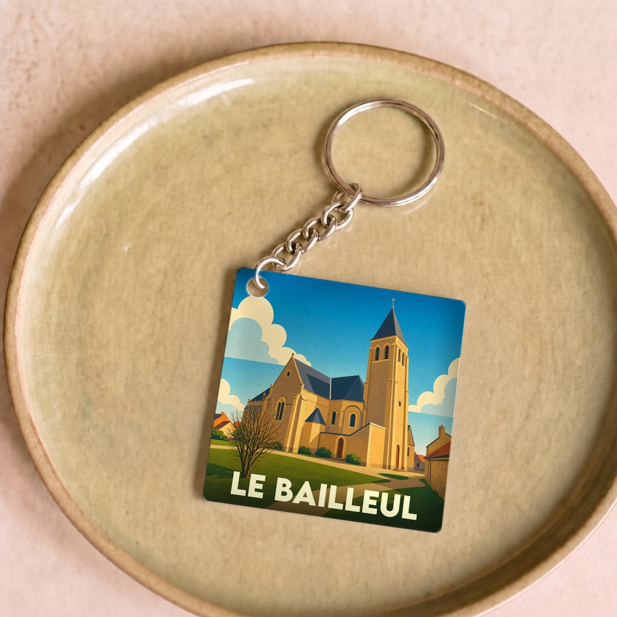 Porte-clés souvenir de la ville de Le Bailleul avec une illustration stylisée de son église.