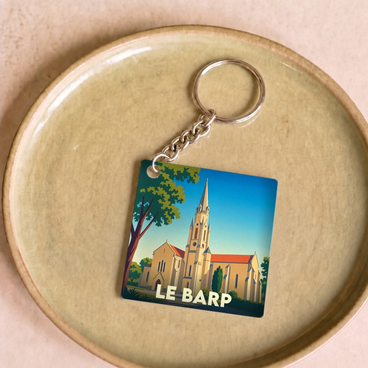 Porte-clés souvenir de la ville du Barp avec une illustration stylisée de son église.
