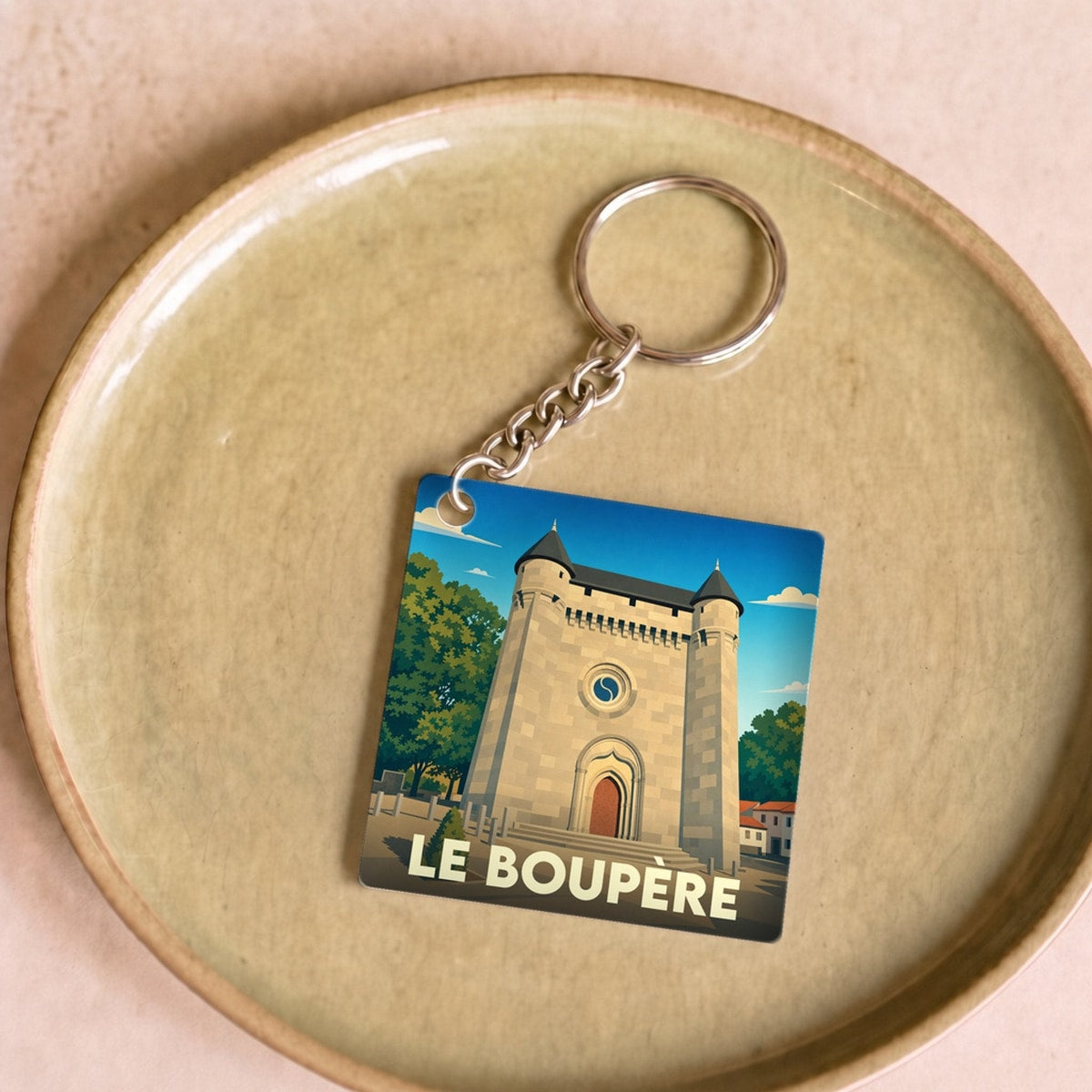 Porte-clés souvenir de la ville du Boupère avec une illustration stylisée de son église fortifiée.