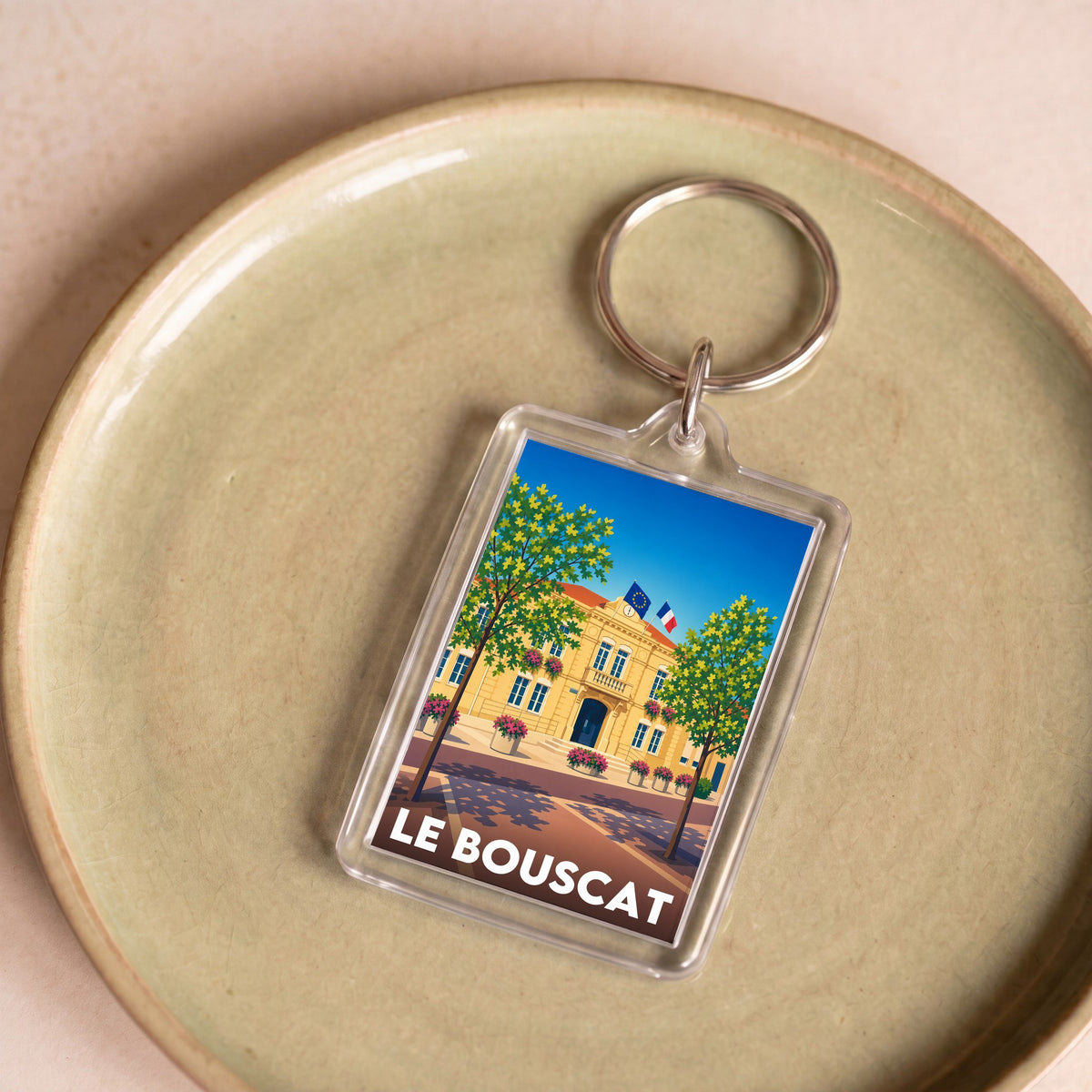 Porte-clés souvenir de la ville de Le Bouscat avec une illustration stylisée de son hôtel de ville.