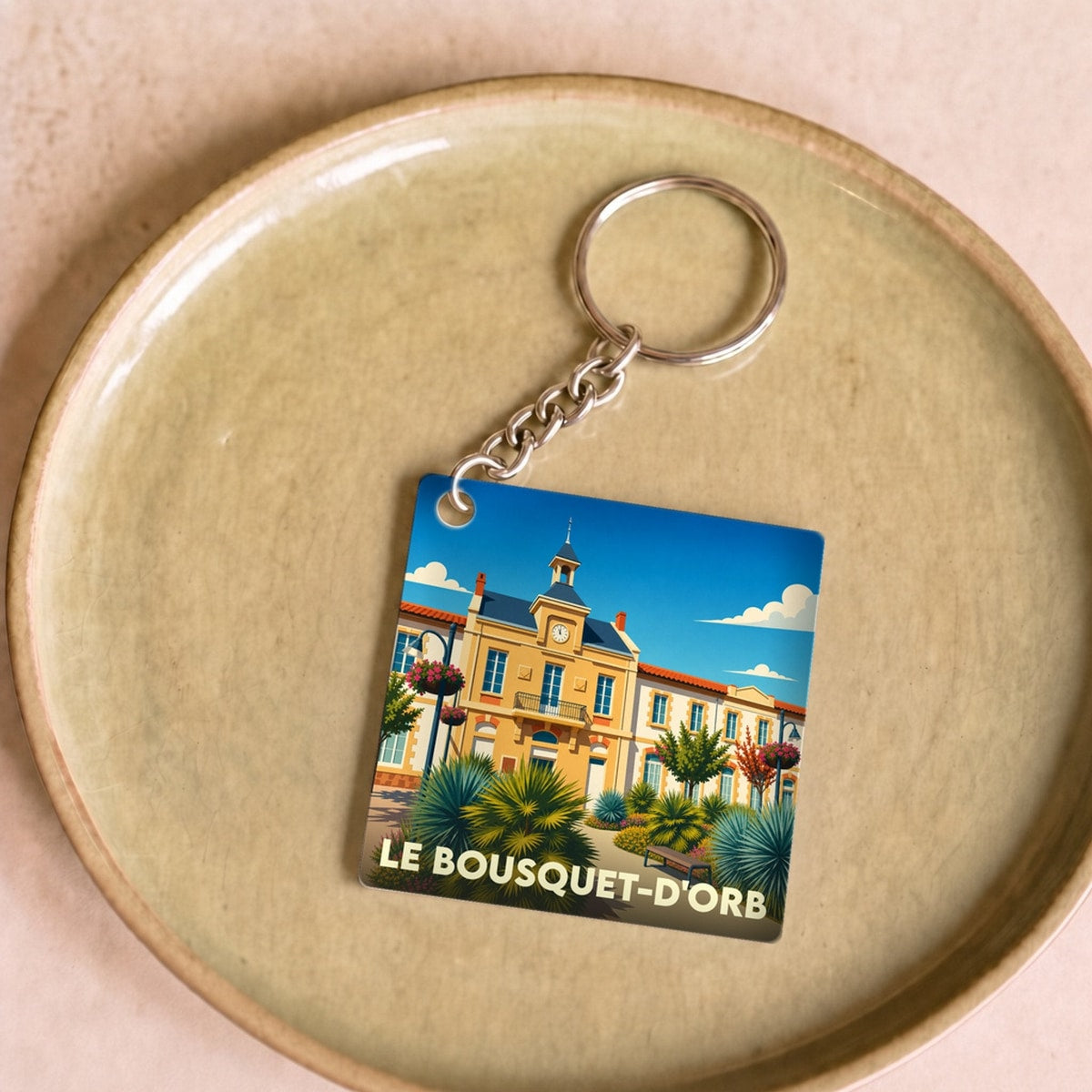 Porte-clés souvenir de la ville de Le Bousquet-d'Orb avec une illustration stylisée de la mairie.