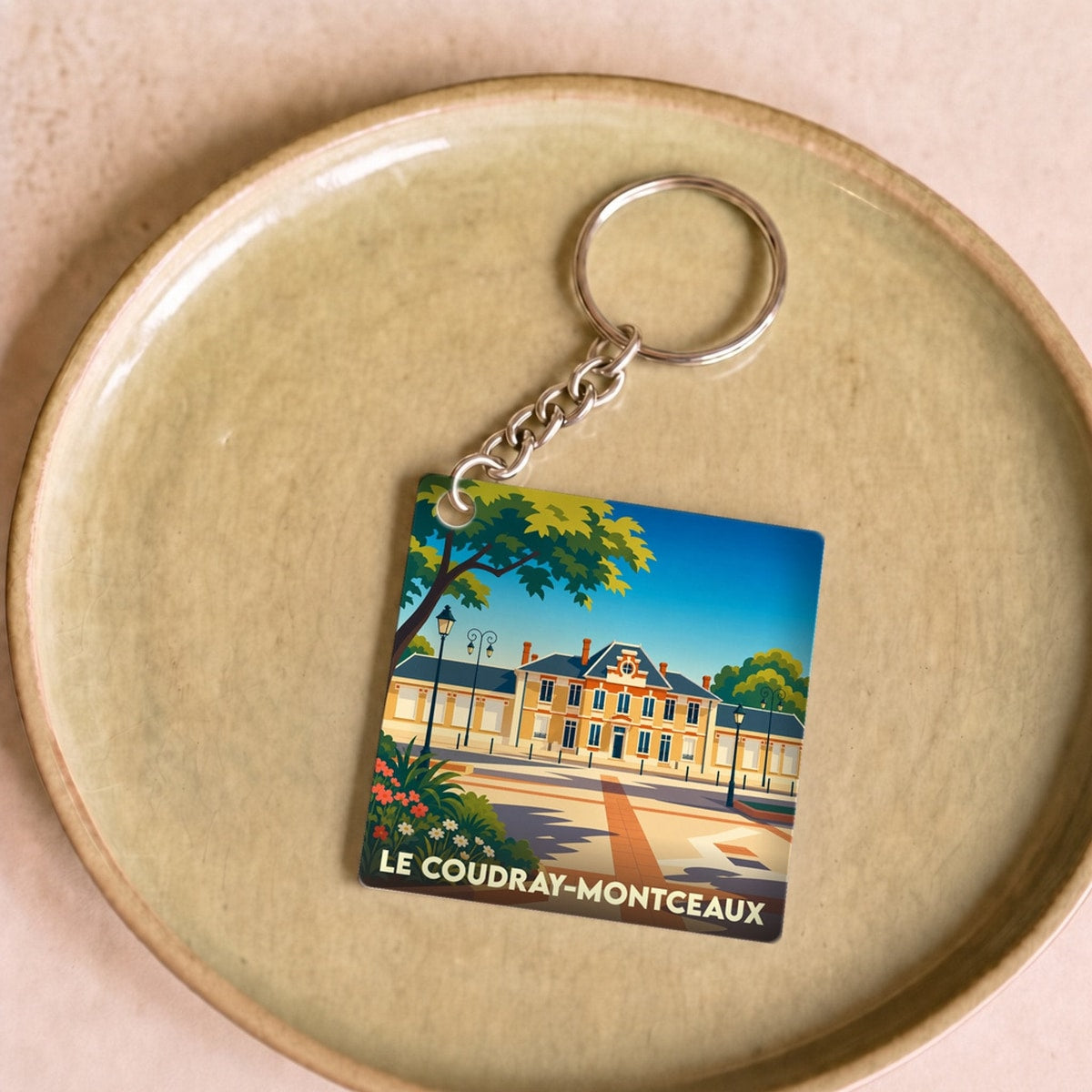Porte-clés souvenir de la ville de Le Coudray-Montceaux avec une illustration stylisée.