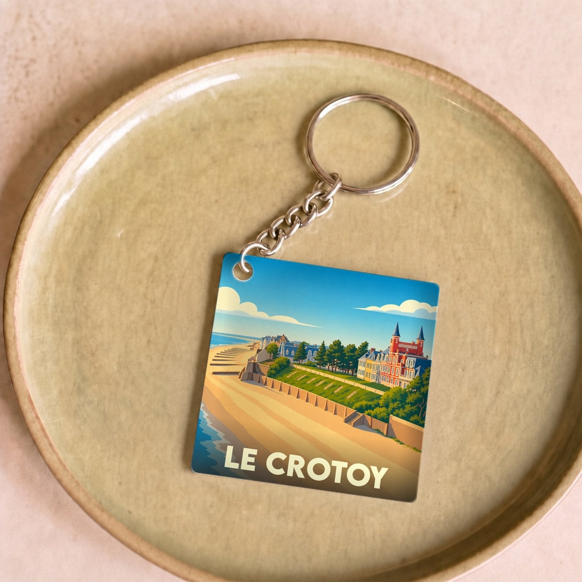 Porte-clés souvenir de la ville du Crotoy avec une illustration stylisée d'une plage et de bâtiments colorés.