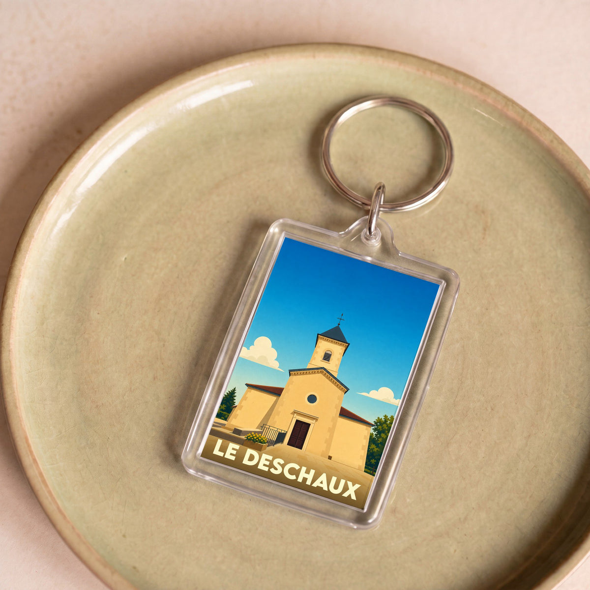 Porte-clés souvenir de la ville de Le Deschaux avec une illustration stylisée de son église.